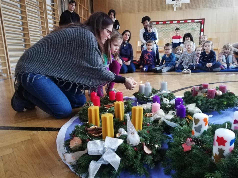 Eine Person, die niederkniet, um eine Kerze auf einem Tisch aufzuheben, in der eine Gruppe von Kindern sitzt