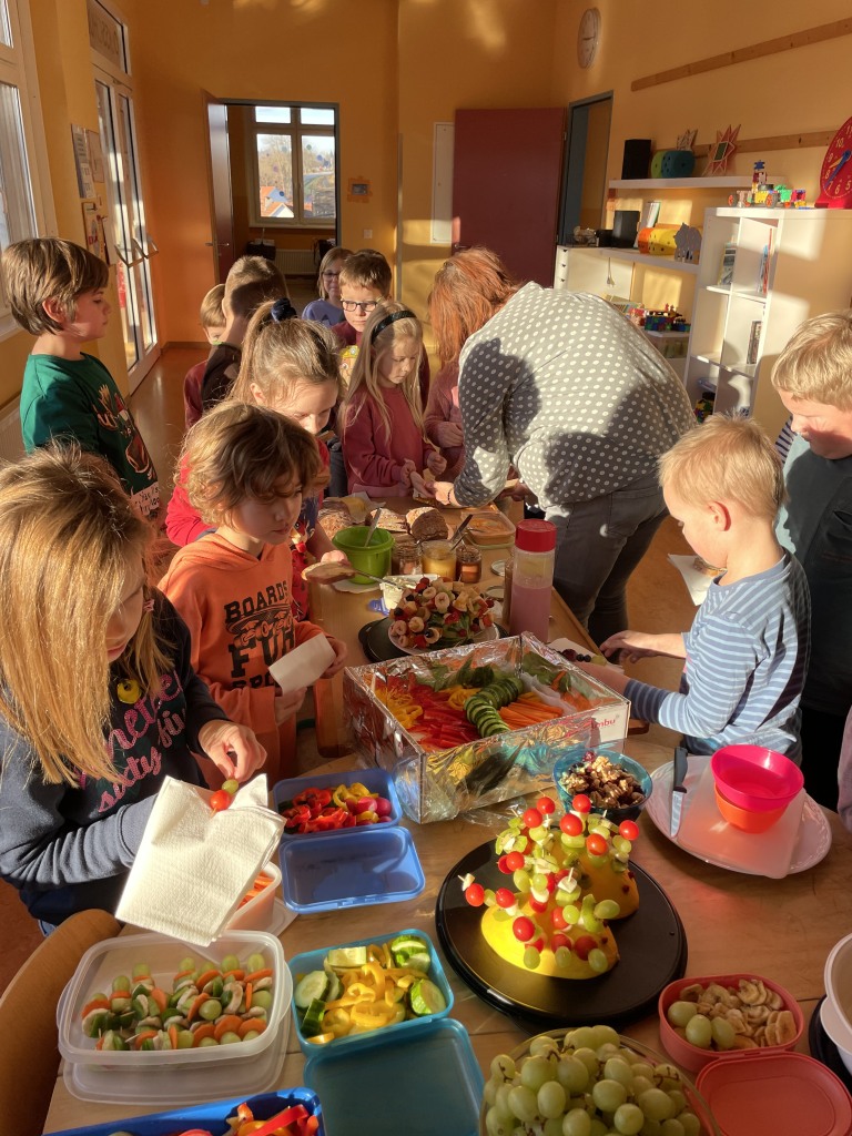 Eine Gruppe von Kindern versammelt sich um einen Tisch voller Essen