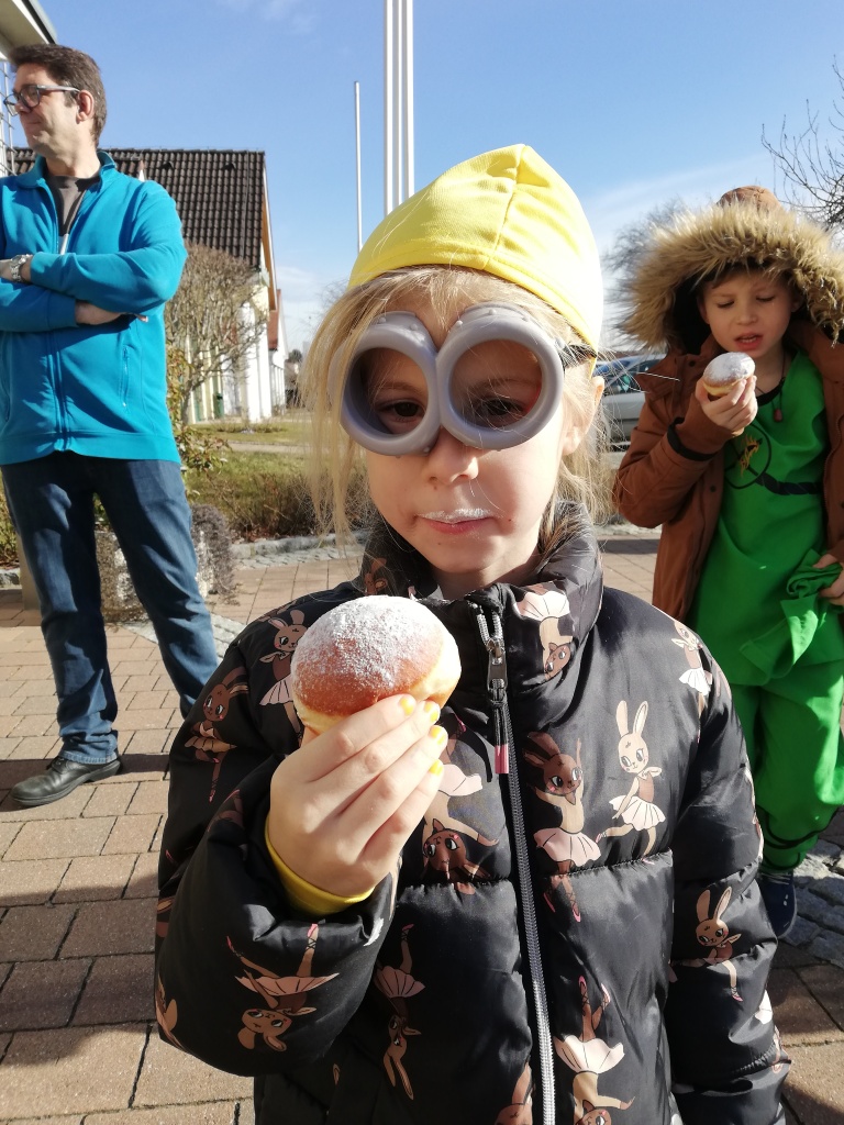 eine Person, die eine Maske trägt und einen Donut isst