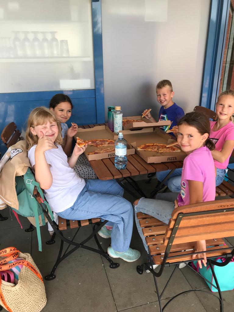 Eine Gruppe von Kindern sitzt an einem Tisch und isst Pizza