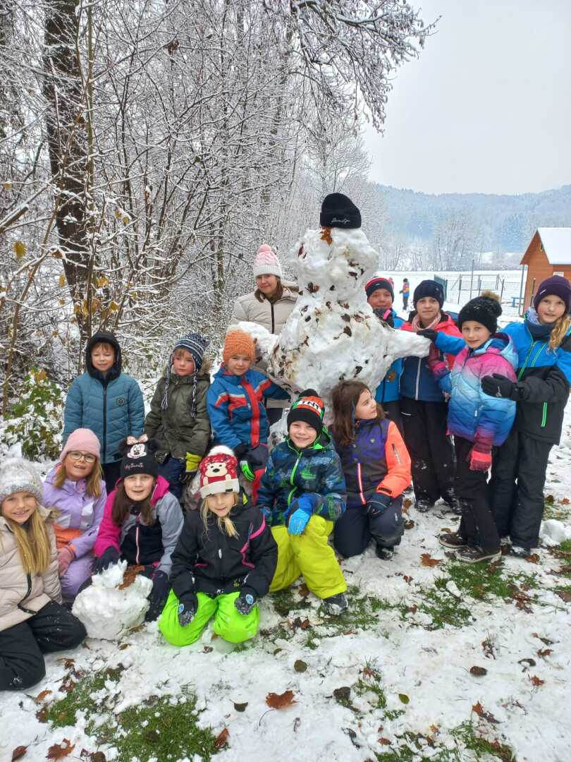 Eine Gruppe von Menschen, die neben einem Schneemann für ein Foto posieren