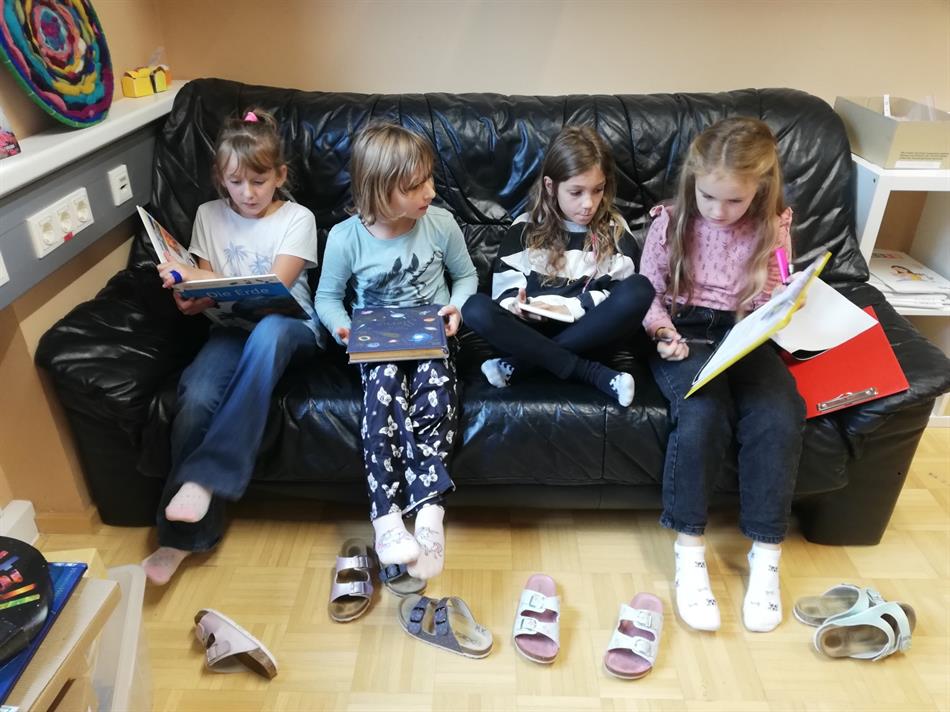 eine Gruppe von Kindern, die auf einer Couch sitzen und Bücher lesen